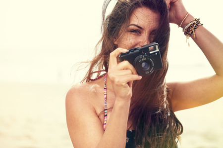 Close up Portrait of beautiful  woman with retro hipster camera having fun at the beachの写真素材