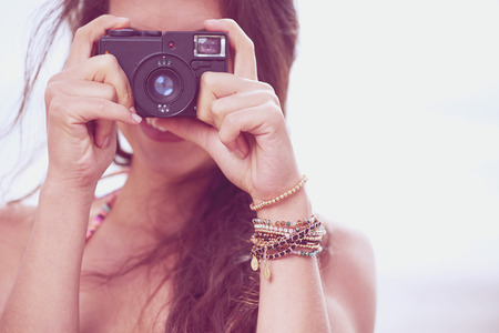 Close up Portrait of beautiful  woman with retro hipster camera having fun at the beachの写真素材