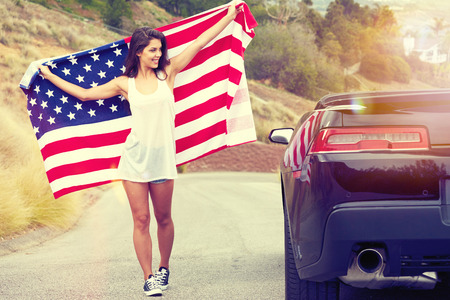 Woman holding American Flag, walking on the streetの写真素材