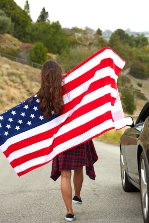 Woman holding American Flag, walking on the streetの写真素材