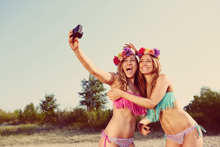 twins taking a photo of themselves on the beachの写真素材