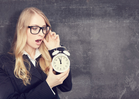 Woman holding with on office clock.chalkboard backgroundの写真素材