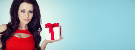 Beautiful woman portrait hold gift in christmas color style . Smiling happy girl on blue background.
