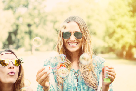 twin sisters making soap bubbles in a parkの写真素材