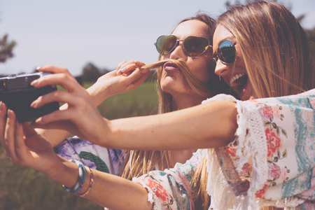 twin sisters making a selfie with retro cameraの写真素材
