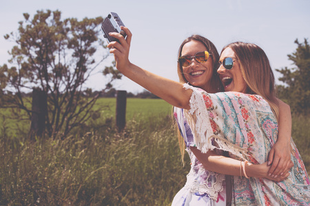 twin sisters making a selfie with retro cameraの写真素材