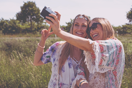 Twin sisters making a selfie with retro cameraの写真素材