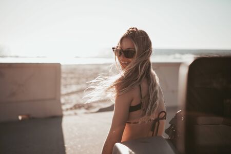surfer girl standing by a car at the beach. california lifestyleの写真素材