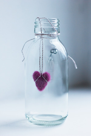 Purple felted heart in glass bottle with a keyの写真素材