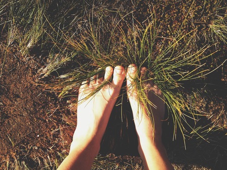 Bare feet entangled in the grassの写真素材