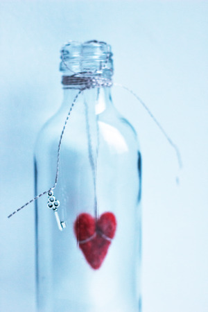 Red felted heart in glass bottle with a keyの写真素材