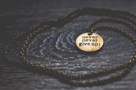 Round brass pendant with words never give upの写真素材