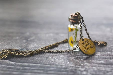 Brass pendant with dry flowers in tiny bottleの写真素材