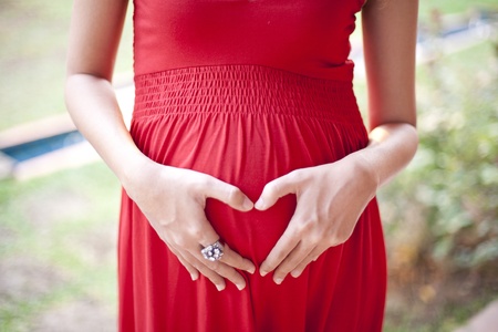 Image of pregnant woman touching her hearth with handsの写真素材