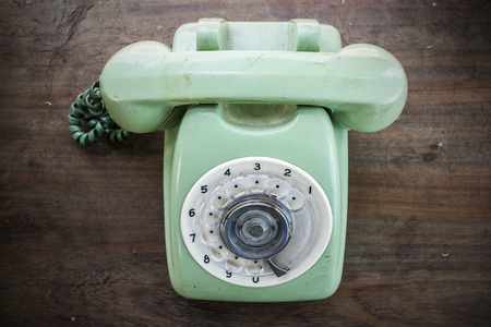 Green vintage telephone on brown wood desk backgroundの写真素材