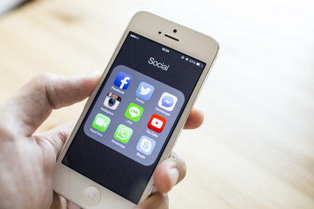 CHIANG MAI, THAILAND - SEPTEMBER 07, 2014: All of popular social media icons on smartphone device screen with hand holding on Apple iPhone 5.のeditorial素材