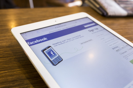 CHIANG MAI, THAILAND - SEPTEMBER 17, 2014: Magnifying glass of Facebook page view on web browser Apple iPad Air device.のeditorial素材