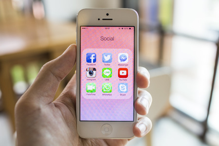 CHIANG MAI, THAILAND - SEPTEMBER 07, 2014: All of popular social media icons on smartphone device screen with hand holding on Apple iPhone 5.のeditorial素材