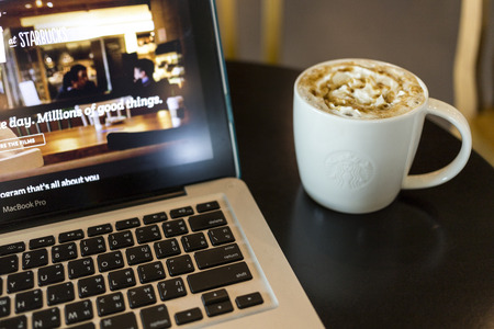 CHIANG MAI, THAILAND - OCTOBER 02, 2014: Starbucks coffee caramel latte and Apple laptop open...