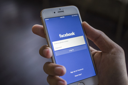 CHIANG MAI, THAILAND - JANUARY 02, 2015: A man trying to log in Facebook application using Apple iPhone 6. Facebook is largest and most popular social networking site in the world.のeditorial素材