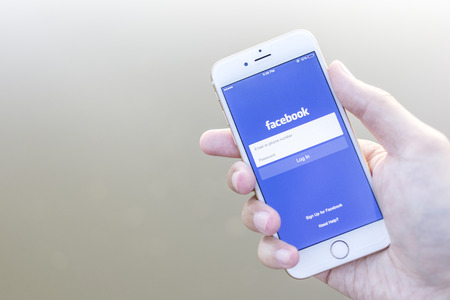 CHIANG MAI, THAILAND - JANUARY 02, 2015: A man trying to log in Facebook application using Apple iPhone 6. Facebook is largest and most popular social networking site in the world.のeditorial素材