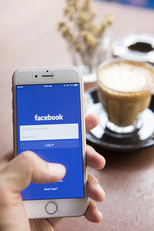 CHIANG MAI, THAILAND - APRIL 22, 2015: A man trying to log in Facebook application using Apple iPhone 6. Facebook is largest and most popular social networking site in the world.のeditorial素材