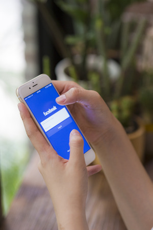 CHIANG MAI, THAILAND - JUNE 28, 2015: Woman trying to log in Facebook application using Apple iPhone 6. Facebook is largest and most popular social networking site in the world.のeditorial素材