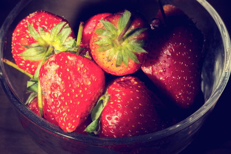 Transparent glass bowl with strawberries on wooden in black backgroundの写真素材