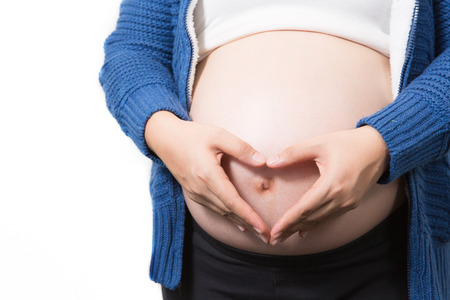 pregnant belly with heart from hands. Isolated over white
