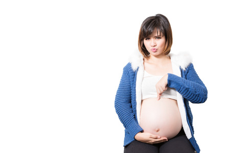 Portrait of the beautiful pointing to the belly 9 month pregnant woman happy posing isolated on white backgroundの写真素材