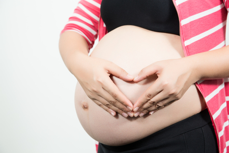 beautiful 9 month pregnant woman with heart from hands. Isolated white background.の写真素材