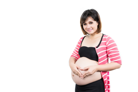 Portrait of the beautiful 9 month pregnant woman with heart from hands. Isolated over whiteの写真素材