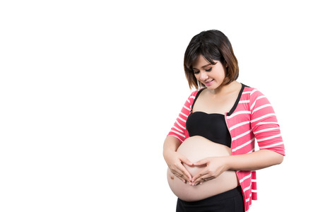 Portrait of the beautiful 9 month pregnant woman with heart from hands. Isolated over whiteの写真素材