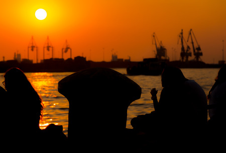 Young people hanging out by the sea in front of Thessaloniki's port watching the sunsetの写真素材