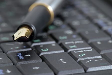 Golden fountain pen on computer keyboard closeupの写真素材