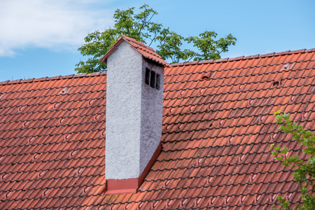 Old style concrete chimney at red clay bricks roof.の写真素材