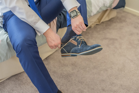 Man with wrist watch putting on hes blue shoes.の写真素材