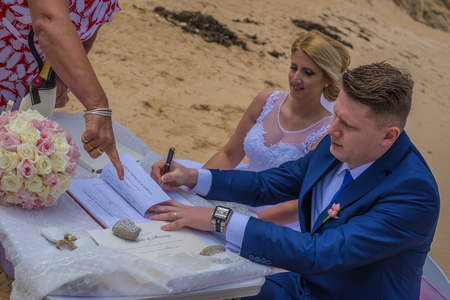 Just married couple signing marriage certificate at beautiful Australian beach.の写真素材