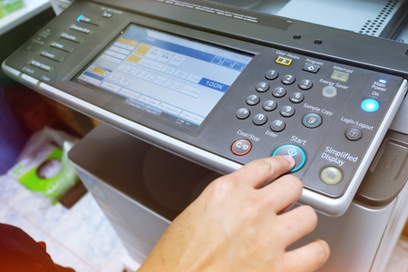 Hand putting a sheet of paper into a copying device