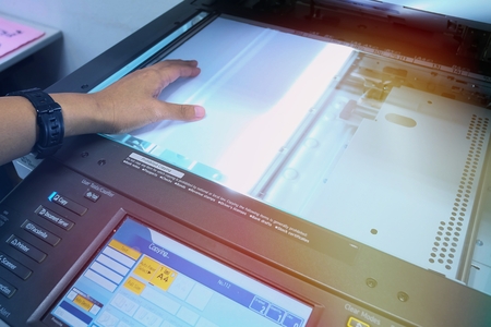 Hand putting a sheet of paper into a copying deviceの写真素材