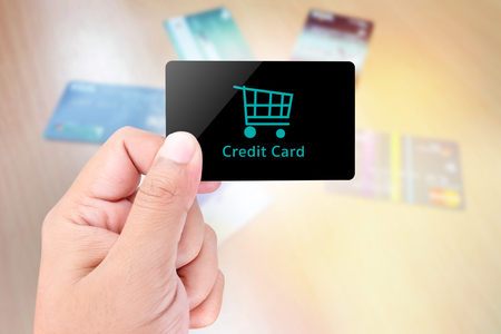 Blank card held by hand on blurred abstract background of credit cardの写真素材