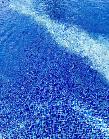 Swimming pool water with ripples and refractions on blue tilesの写真素材