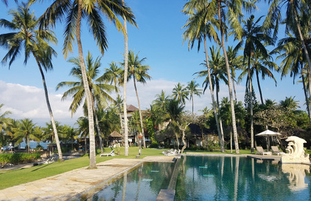CANDIDASA, BALI, INDONESIA - MAI 14, 2017: Pool amenities surrounded by palm trees, in a Balinese beach resort for travel backgrounds.のeditorial素材