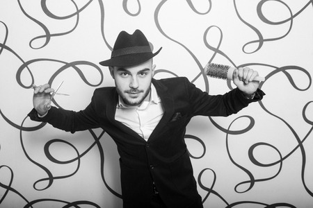 Fashion portrait of a professional hairdresser. Man wearing shirt and hatの写真素材