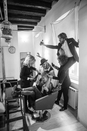 Makeup and hairstyle process. Makeup artist and hairdresser work in tandem, curl and color model in the salon. Three beautiful women and manの写真素材