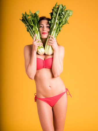 Focus on chicory. Beautiful woman is smiling and looking aside. Isolated on a yellow backgroundの写真素材