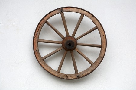 Old wheel of a cart on a white wallの写真素材