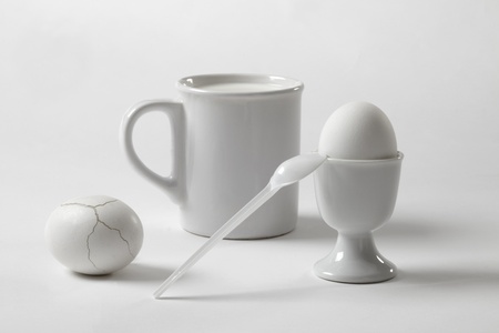 White still life in high key with a mug and an cracked eggの写真素材
