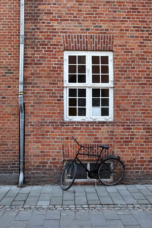Black bicycle from an old brick wall with a window and downspoutの写真素材