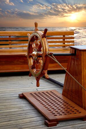 Old wooden ships helm on background of sea sunset